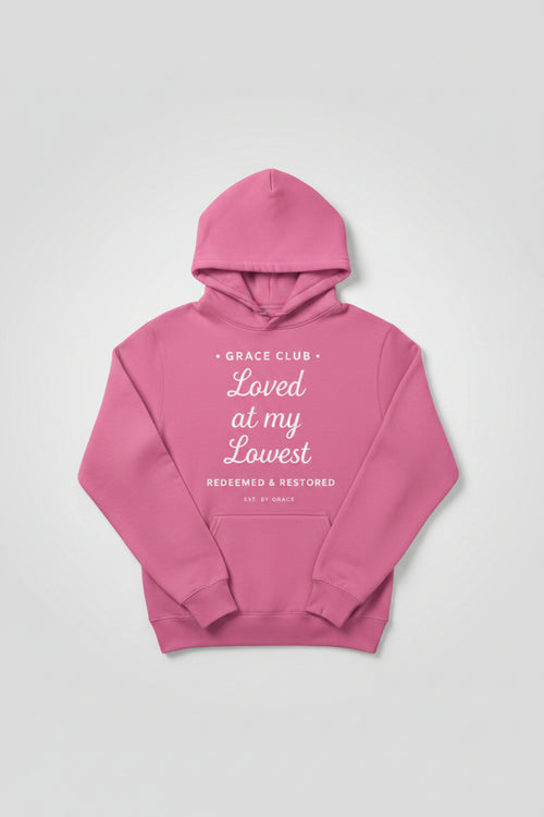 Pink hoodie with text 'Grace Club Loved at my Lowest Redeemed & Restored EST. BY GRACE' on a white background